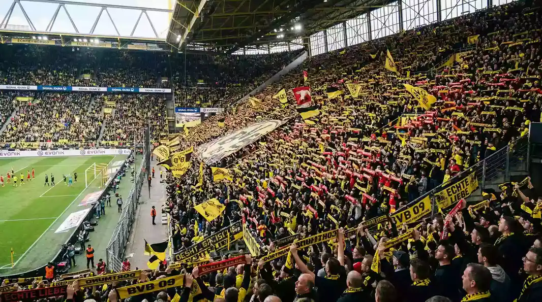 Gradas repletas de aficionados con bufandas y banderas durante un partido de la Bundesliga