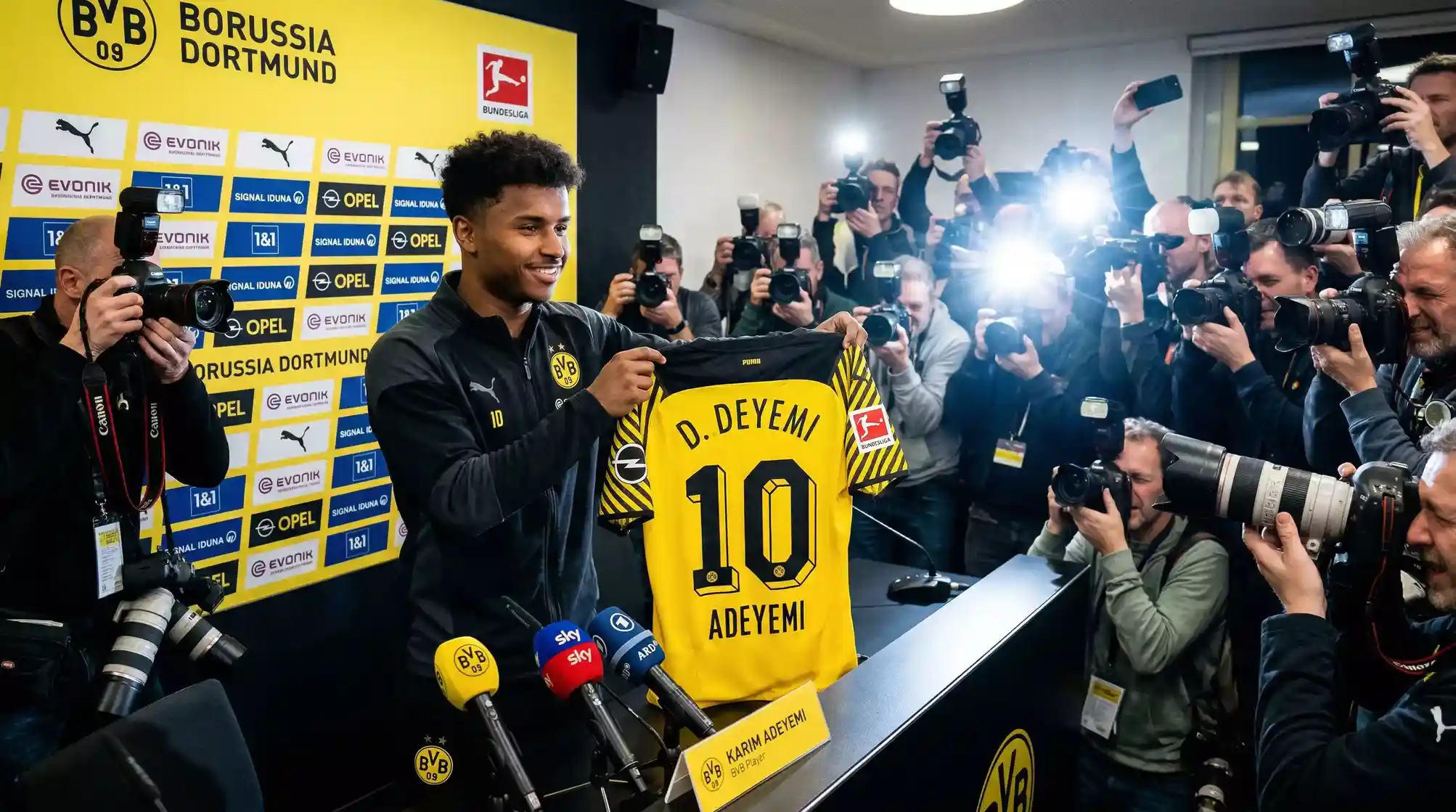 Jugador de futbol posando con la camiseta de su nuevo club de la Bundesliga el dia de su presentacion
